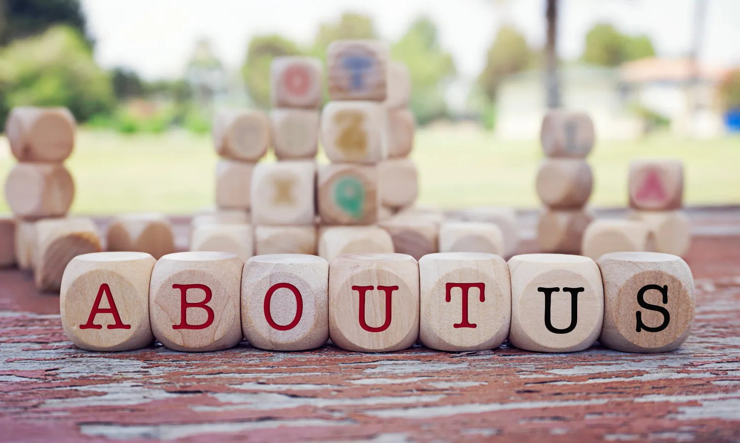 Wooden letter blocks spelling about us resting outdoors on a weathered surface